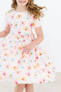 Girl wearing white butterfly print twirl dress for girls by Mila & Rose spinning with smile