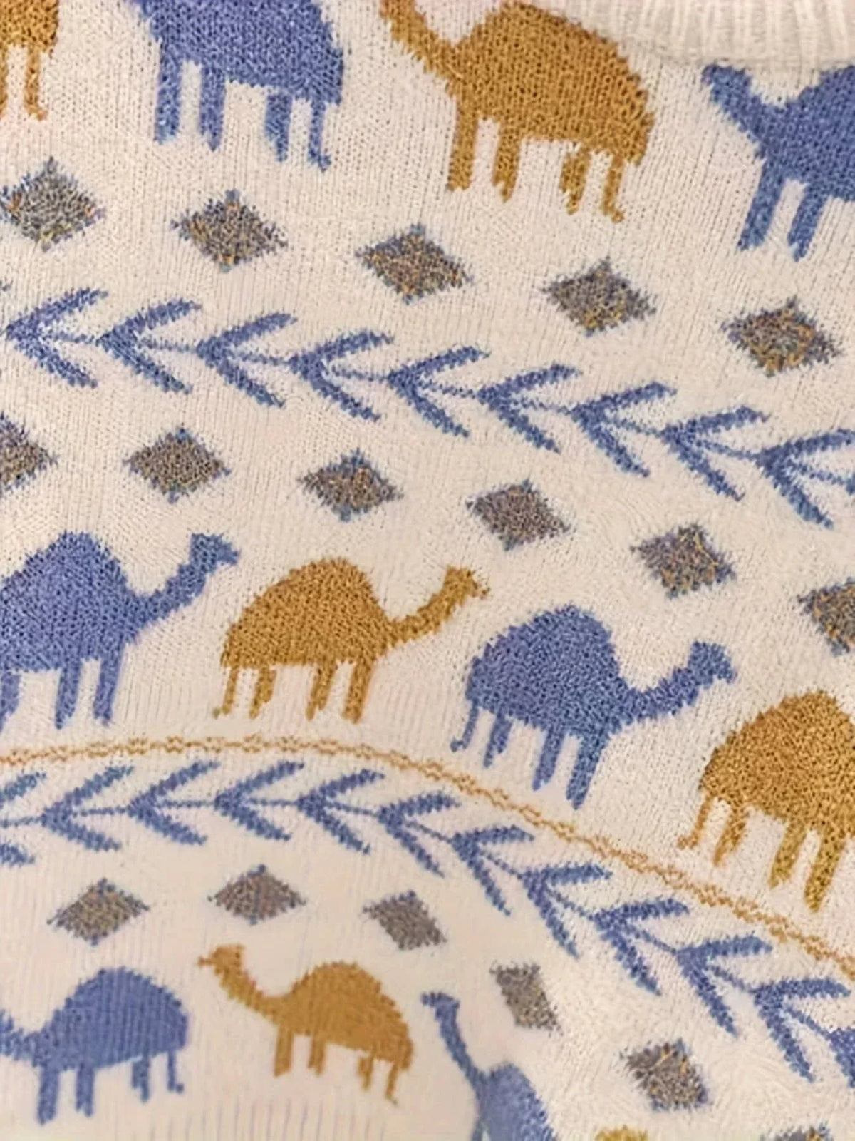 Close-up of cream boys knit sweater with blue and brown camel pattern for toddlers