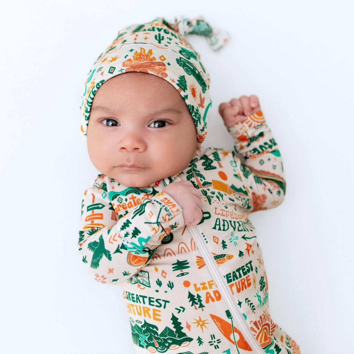 Baby wearing a patterned outfit and hat on a white background