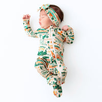 Baby in a patterned onesie and headband on a white background