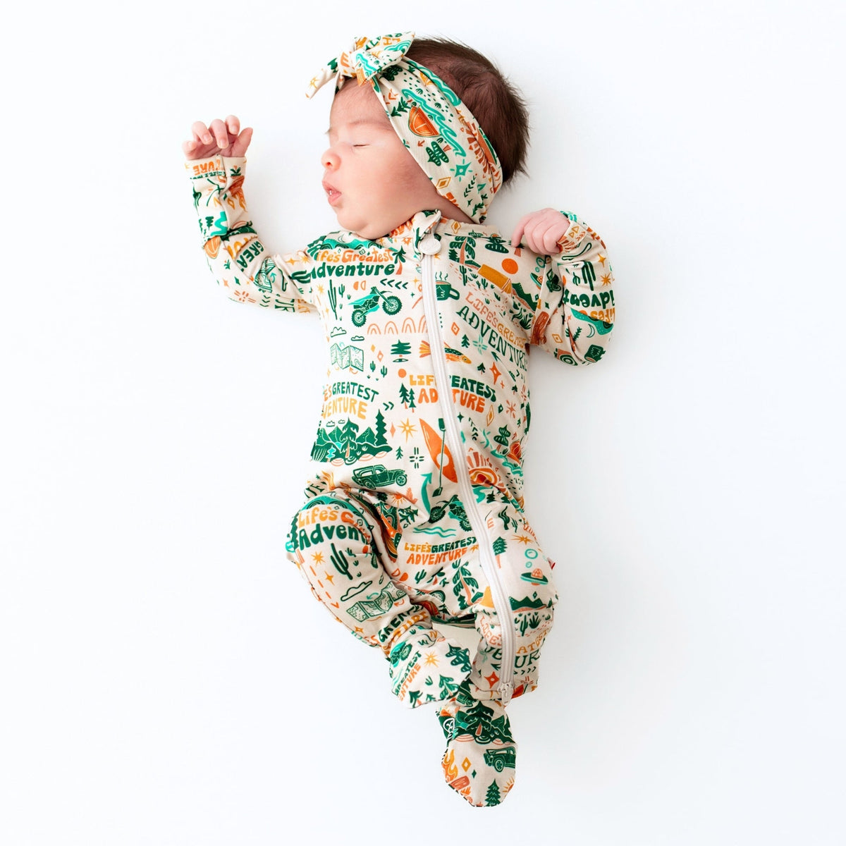 Baby in a patterned onesie and headband on a white background