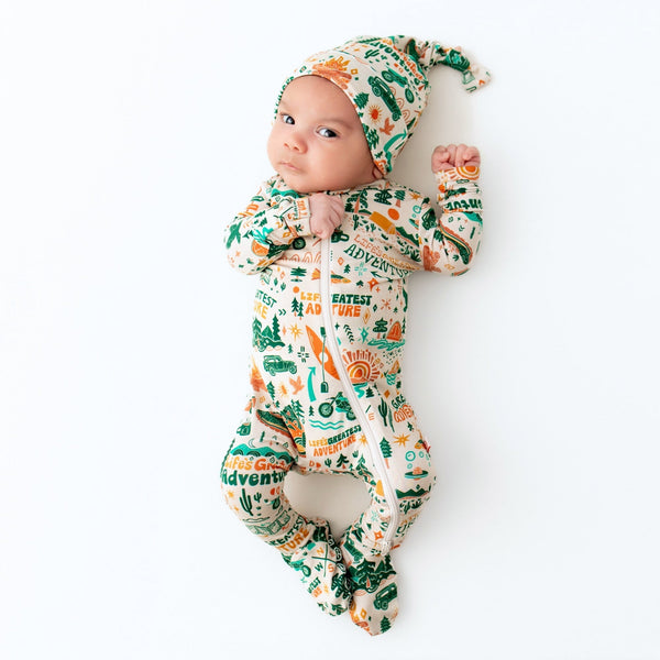 Newborn baby wearing a patterned outfit and hat on a white background