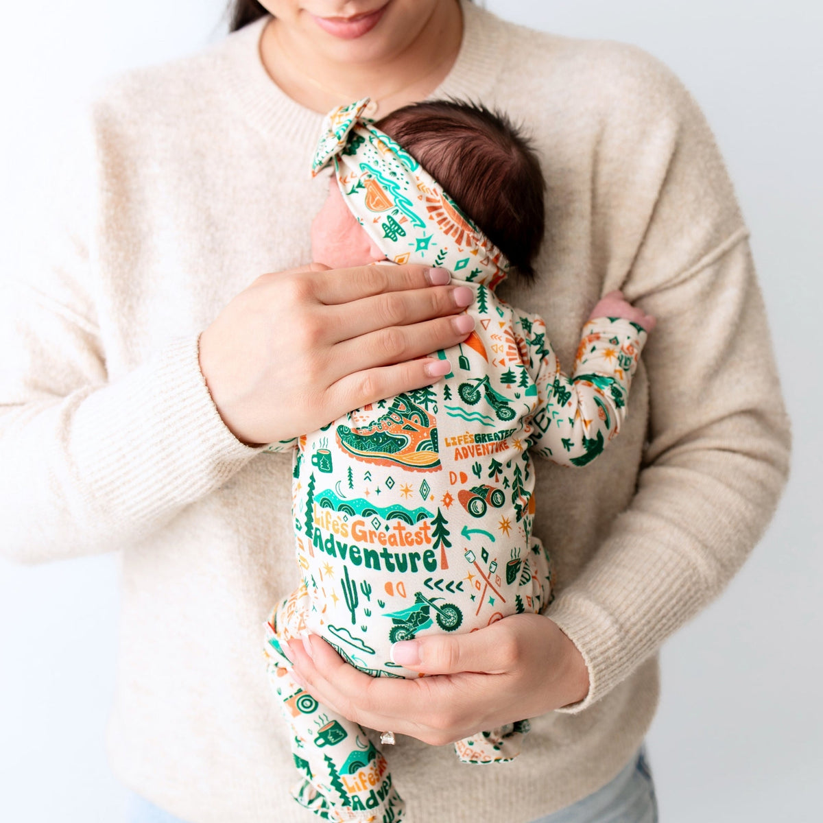 Person holding a baby wrapped in a patterned blanket with text and graphics.