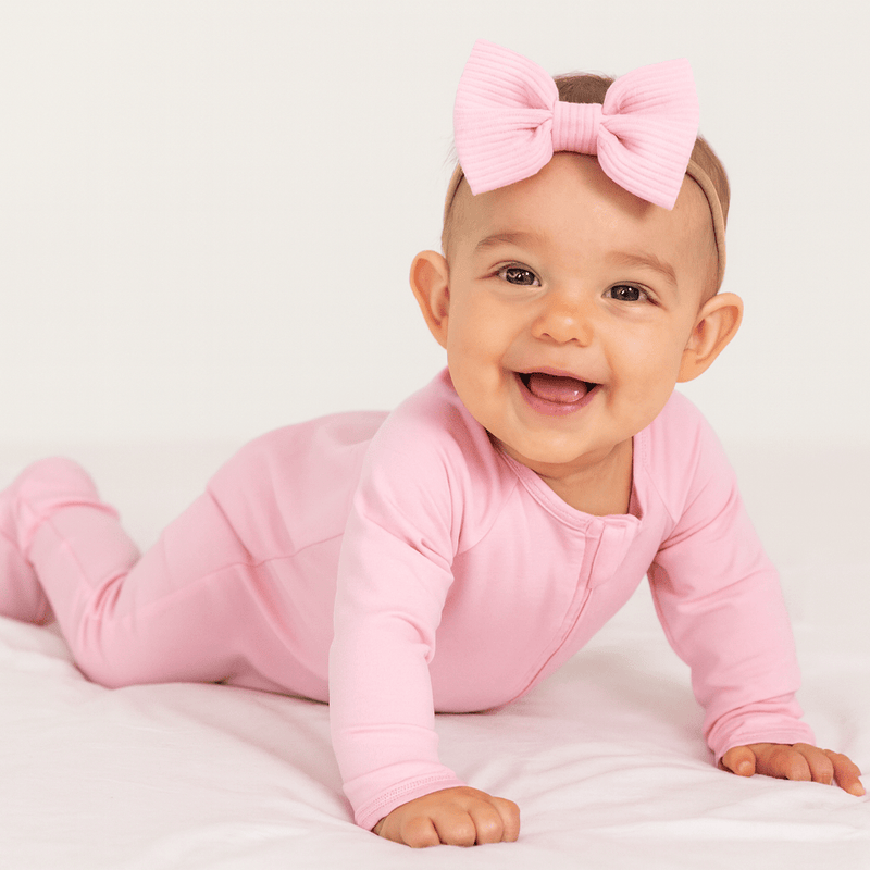 Baby in pink outfit with a large bow on a white background