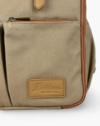Macro shot of coarse beige canvas weave, metal zipper pull, and embossed tan leather Baldwin Baby Co brand patch