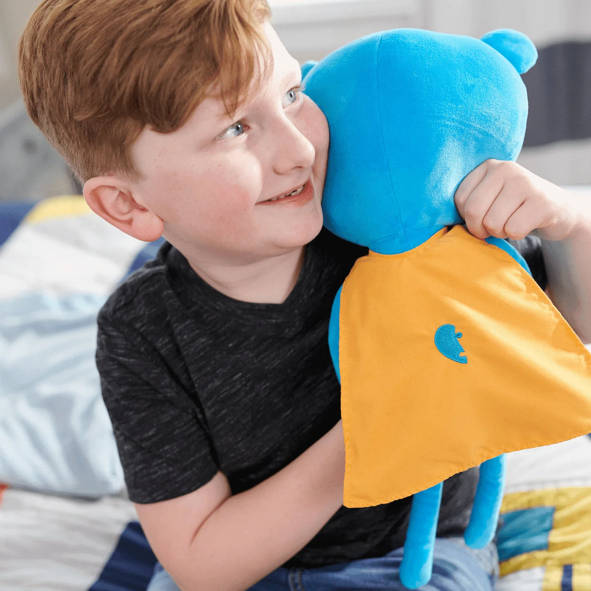 Blue and yellow fabric cape bear plush doll for toddlers made of soft plush material held by smiling boy