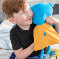 Blue and yellow fabric cape bear plush doll for toddlers made of soft plush material held by smiling boy