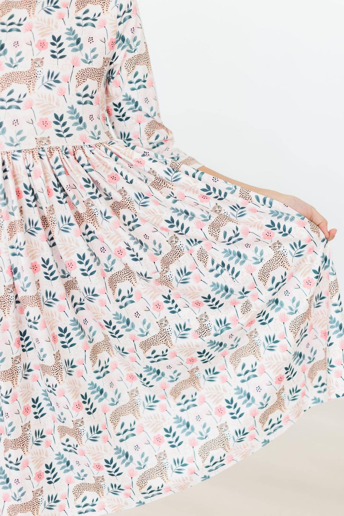 Young girl wearing Mila & Rose cheetah twirl dress for girls in soft pastel colors holding skirt out
