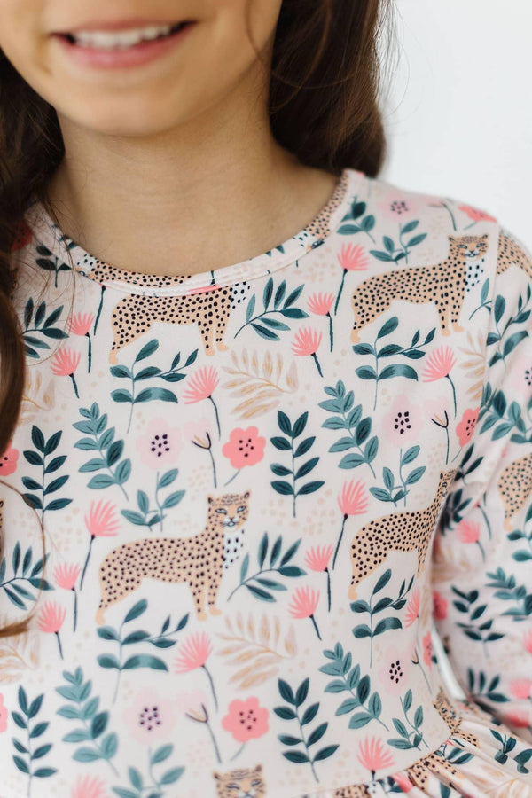 girl wearing pink cheetah twirl dress for girls with floral and leaf print in a playful pose
