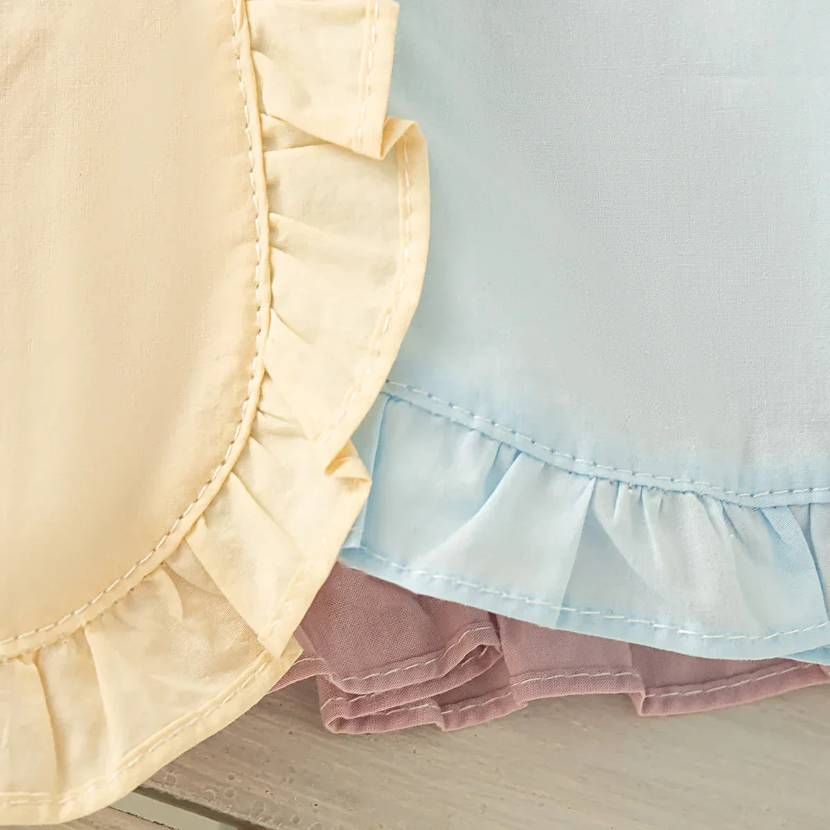 babies pastel yellow blue and mauve party dress with ruffled hem detail