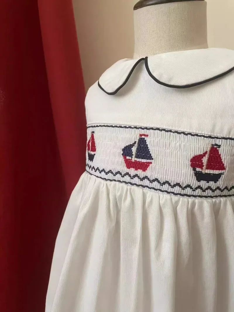White baby party dress with black trim collar and red navy boat embroidery on chest