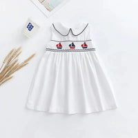white baby party dress with black trim and embroidered red and blue sailboats sleeveless