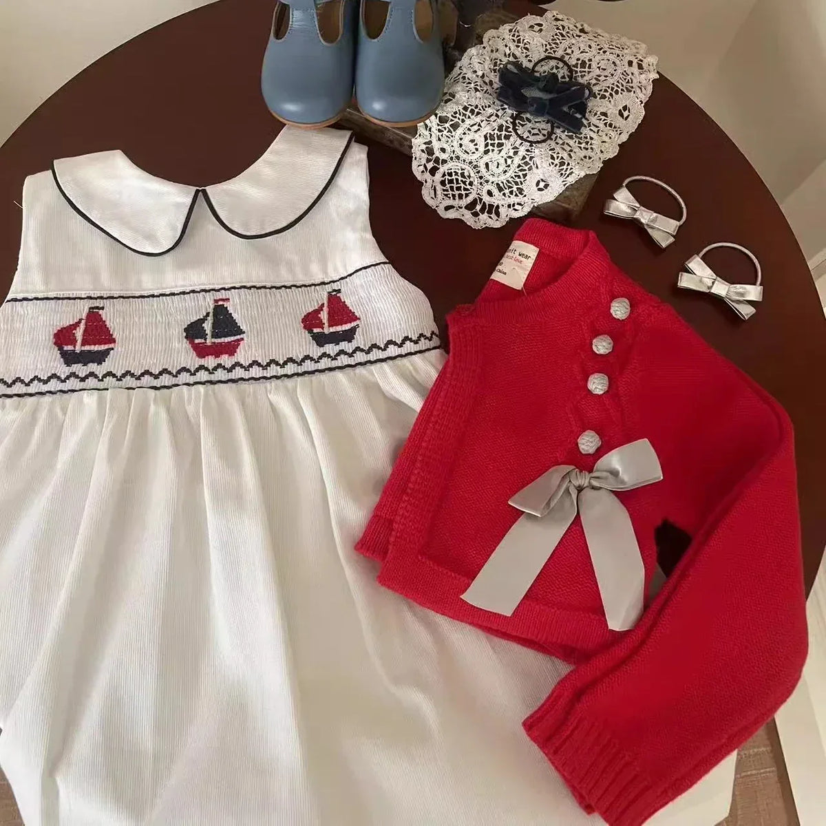 White baby party dress with sailboat embroidery, red long sleeve cardigan with bow, blue shoes and lace headband
