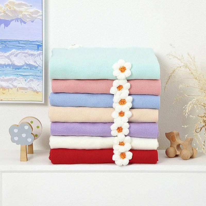 Stack of pastel-colored baby blankets with white flower accents children’s flower blankets for infants