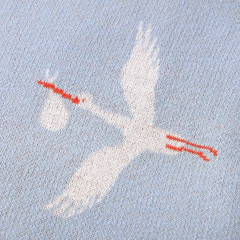 Blue children's knit blanket with white stork carrying bundle design for babies and kids