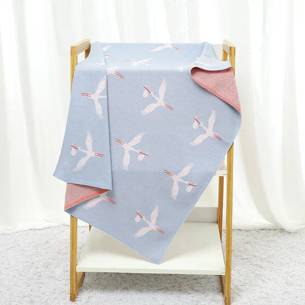 Blue and pink children's knit blanket with white stork bird pattern, suitable for babies and kids