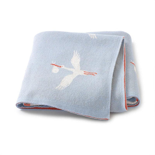 Light blue children's knit blanket with white stork design and red trim for babies and kids
