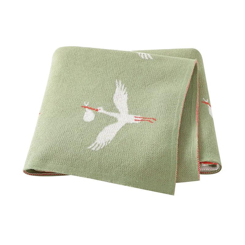 green children's knit blanket with white stork design, suitable for babies and toddlers