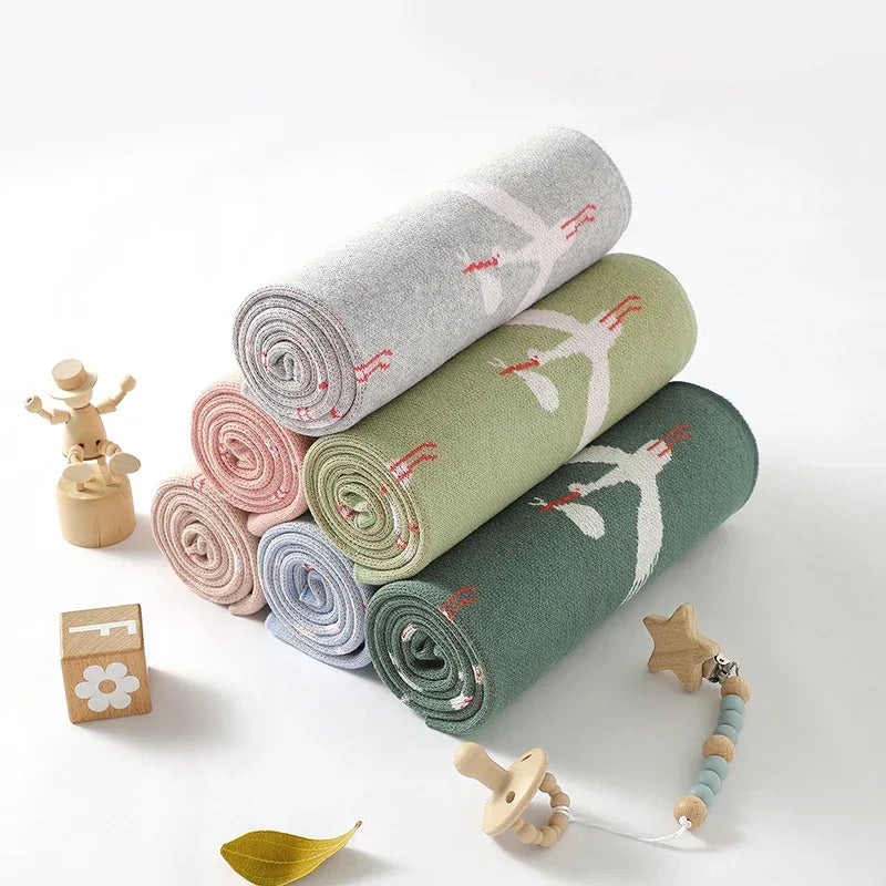 Children's knit blanket rolled in pastel colors with bird pattern, suitable for babies and kids