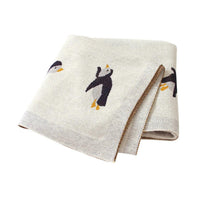 beige childrens knit penguin blanket with black and orange penguin design for babies and kids