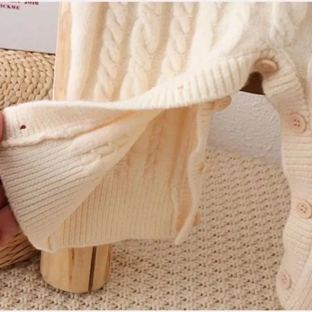 close-up of cream classic cable knit baby romper for newborns showing button snap details