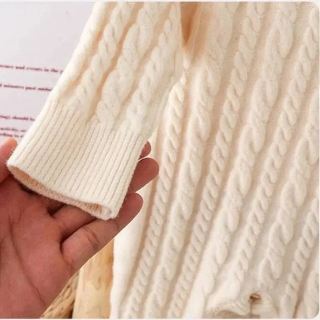 close-up of hand holding cream classic cable knit baby romper sleeve for infants