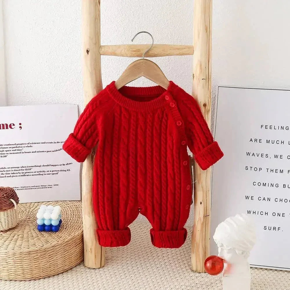red classic cable knit baby romper for infants hanging on wooden ladder with rolled sleeves and legs