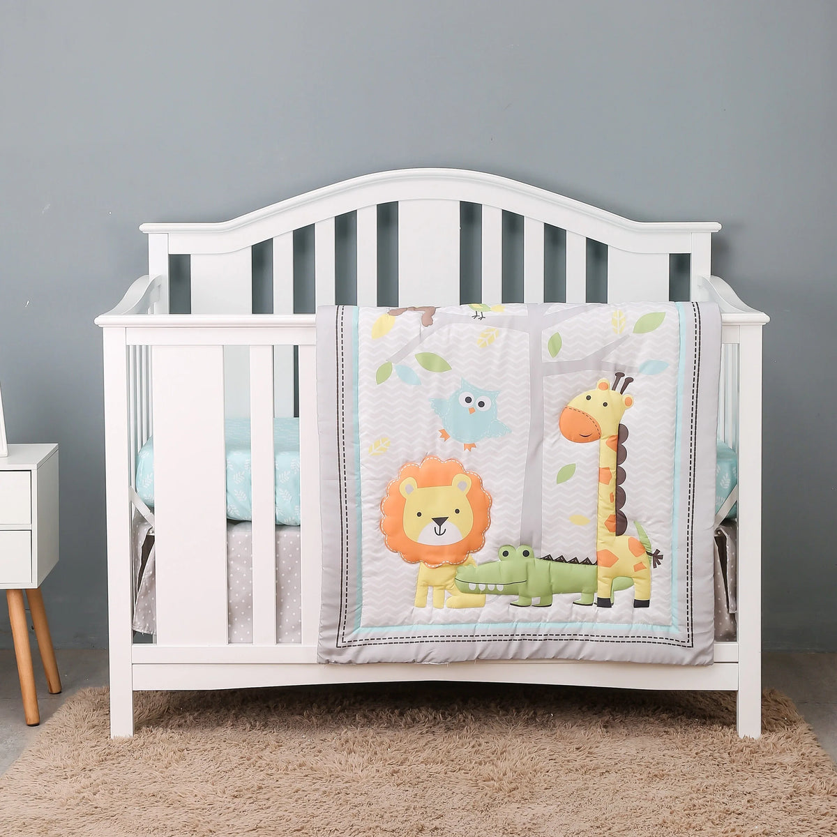 White baby crib with blue comfort set featuring lion giraffe and crocodile cartoon designs for infants