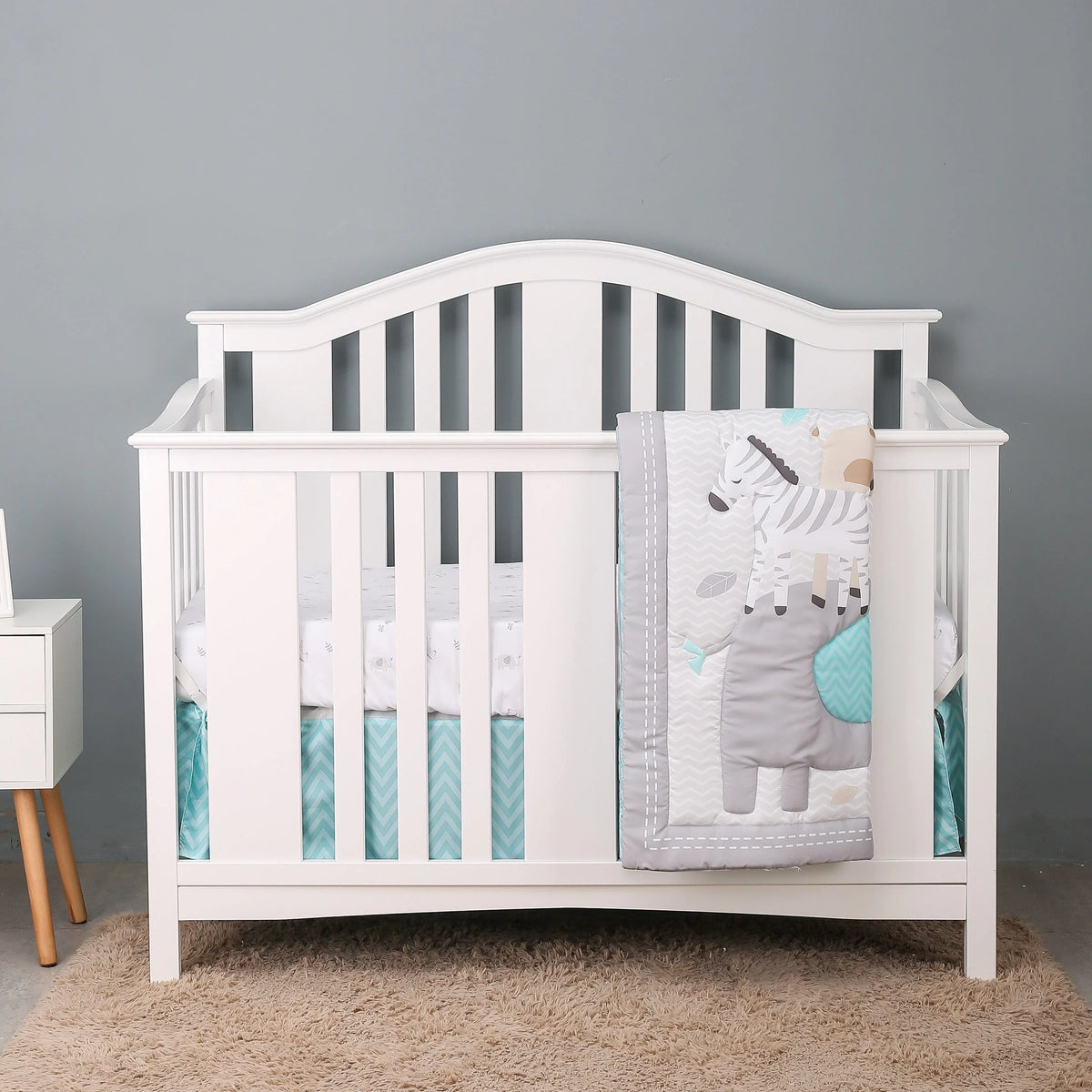 white baby crib with gray and blue zebra comfort set blanket draped over side for infants