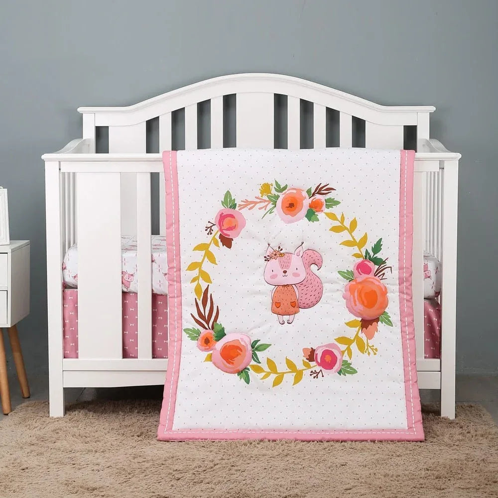 baby pink floral comfort set with squirrel design hanging on white crib in nursery