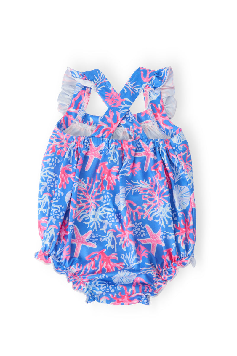coral print baby romper in blue with pink sea creatures and white ruffle cross back for infants