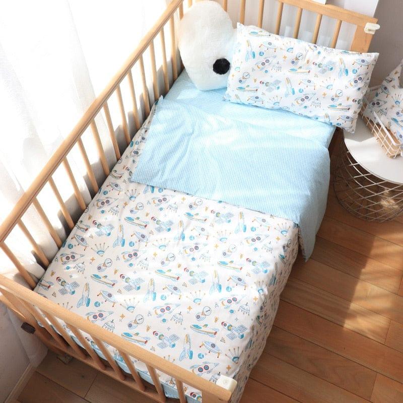 Boys nursery crib bedding set with blue and white space-themed design and light blue blanket
