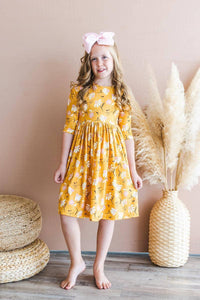 young girl wearing yellow dandelion twirl dress for girls with 3/4 sleeves smiling indoors