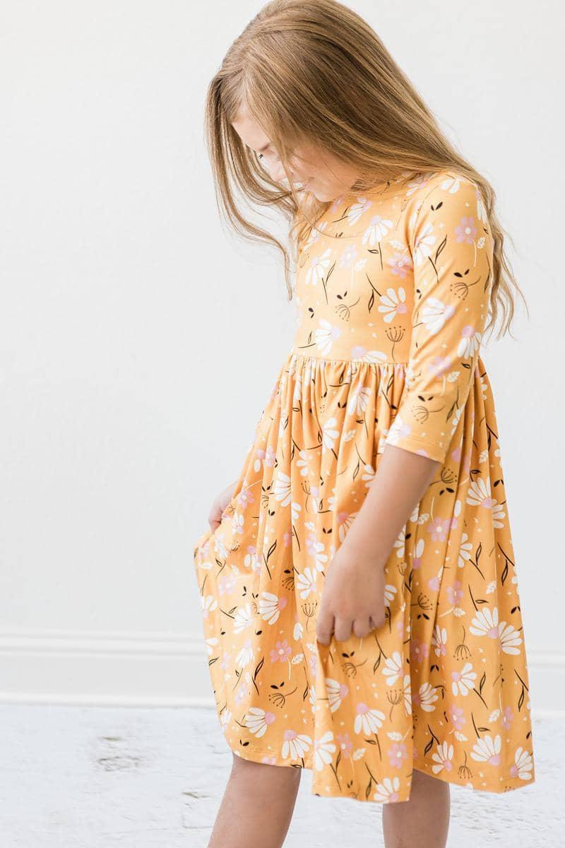 young girl wearing dandelion twirl dress for girls by Mila Rose in a standing pose with hands in pockets