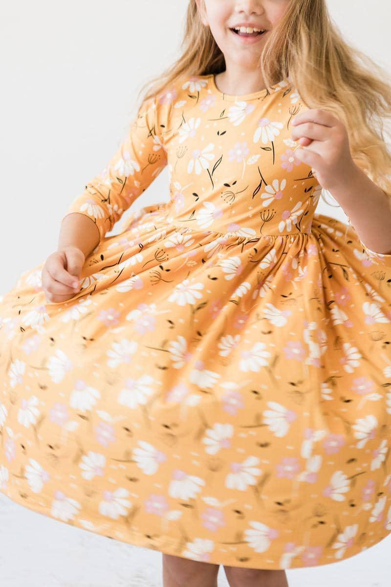 young girl wearing a dandelion twirl dress for girls in yellow floral pattern twirling around