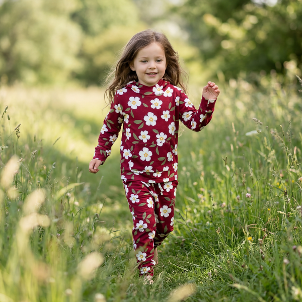 Child running through a field in a red floral matching hooded jogger set with front pocket.