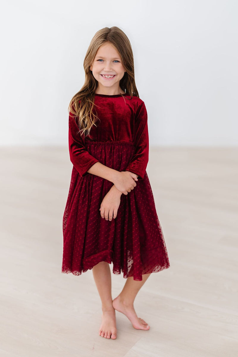 A smiling girl in a Cranberry Velvet Tutu Dress, showcasing the soft fabric and elegant style, perfect for special occasions.