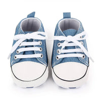 Pair of blue denim baby first walkers with white laces and rubber toes for infants