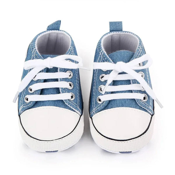 Pair of blue denim baby first walkers with white laces and rubber toes for infants
