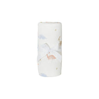 white dinosaur knit baby blanket with pastel dinosaur prints tied with white ribbon newborn size