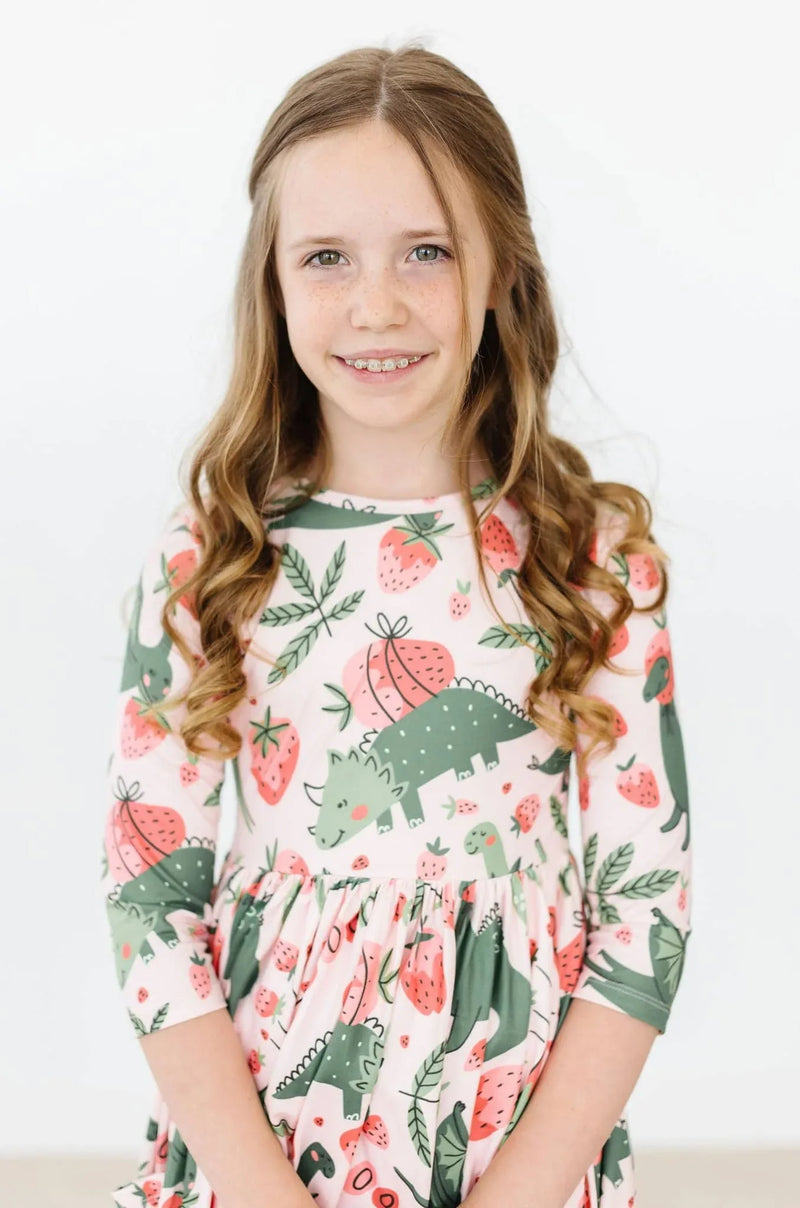 girl wearing pink and green dinosaur twirl dress for girls with 3 quarter sleeves smiling