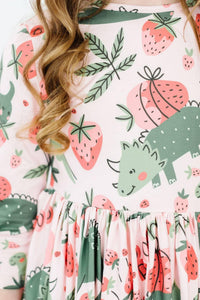 close-up of girl wearing pink dinosaur twirl dress for girls with strawberries and leaves print