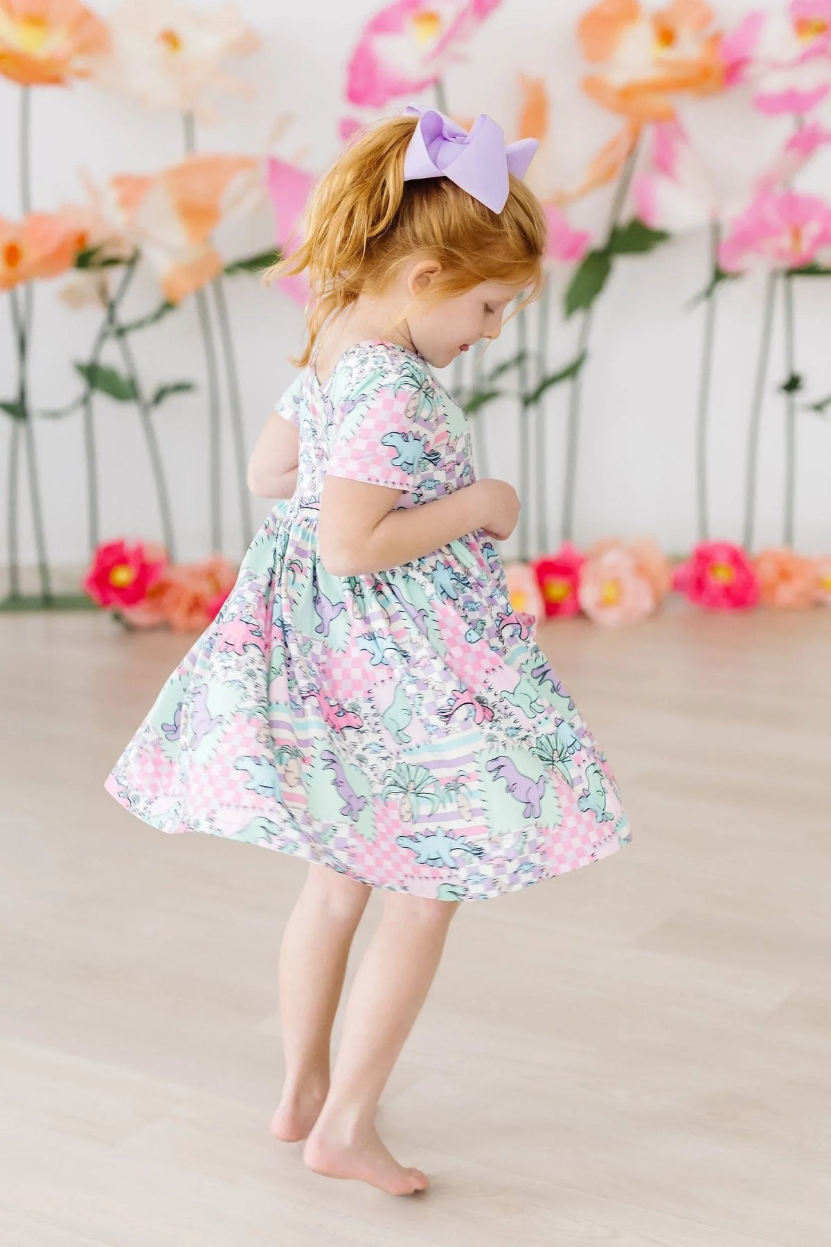 Young girl wearing pastel dinosaur twirl dress for girls by Mila & Rose spinning indoors