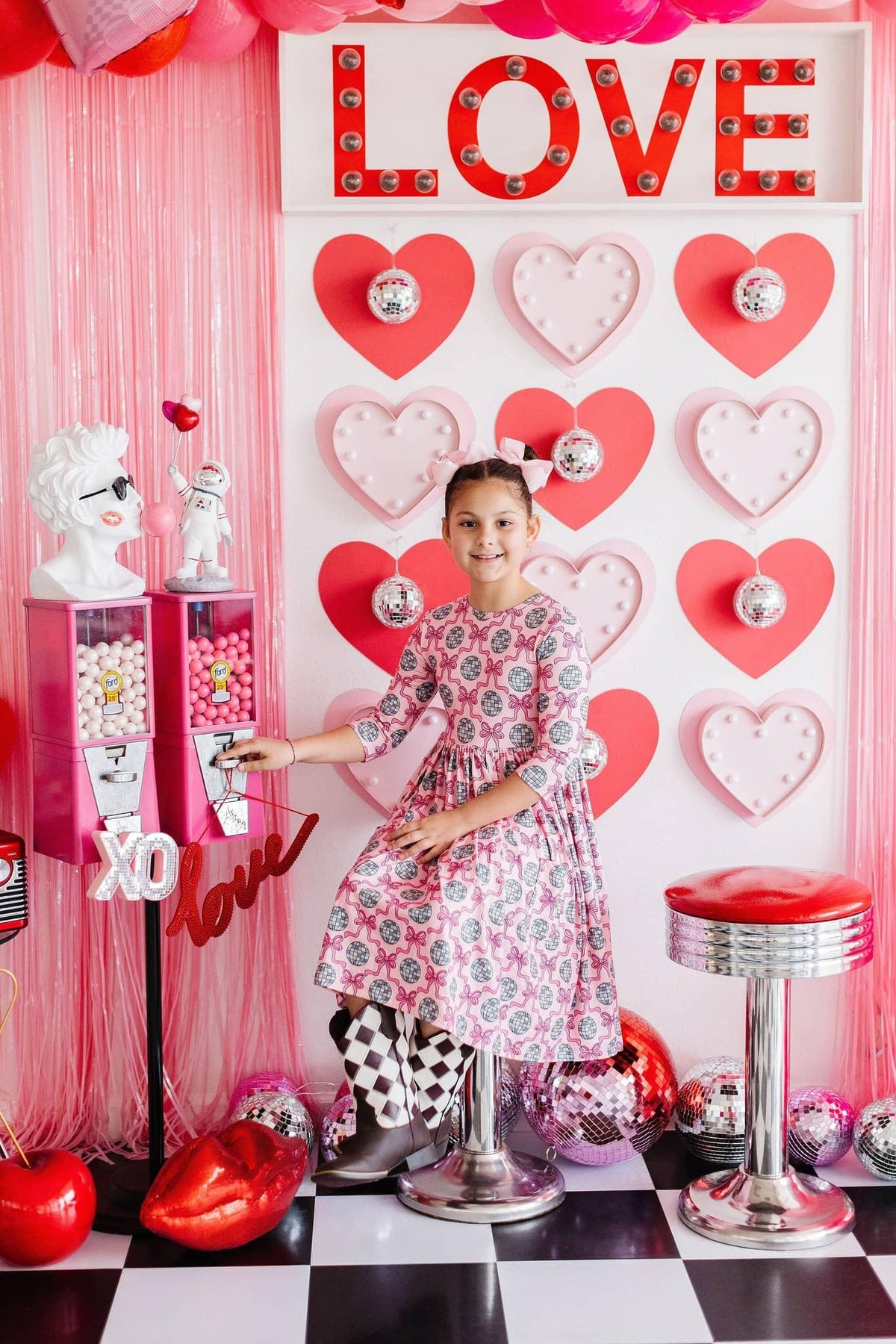 Girls pink floral disco bow twirl dress for girls with 3/4 sleeves by Mila & Rose sitting in retro themed room