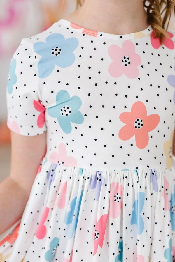 young girl wearing white dots and daisies pocket dress for girls twirling indoors
