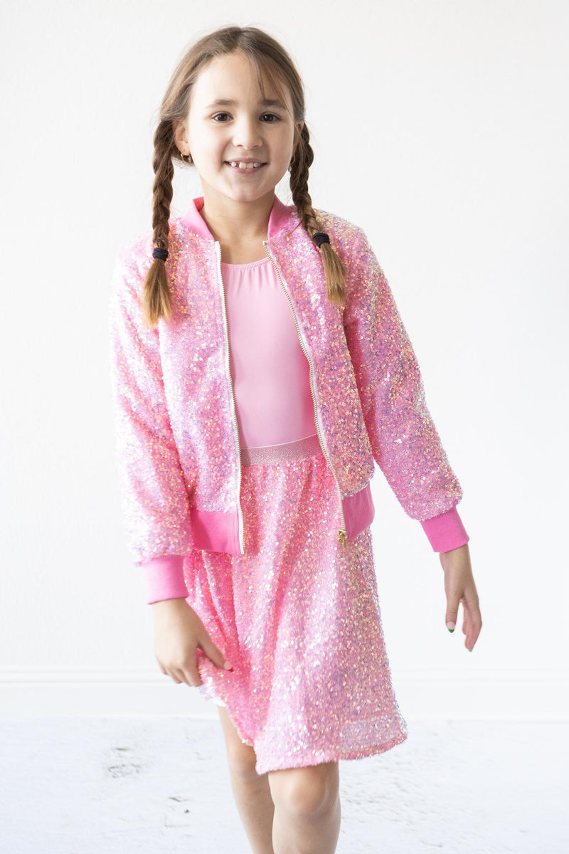 Smiling girl in a Bubblegum Pink Sequin Jacket confidently walking, showcasing her sparkling outfit with a joyful expression.