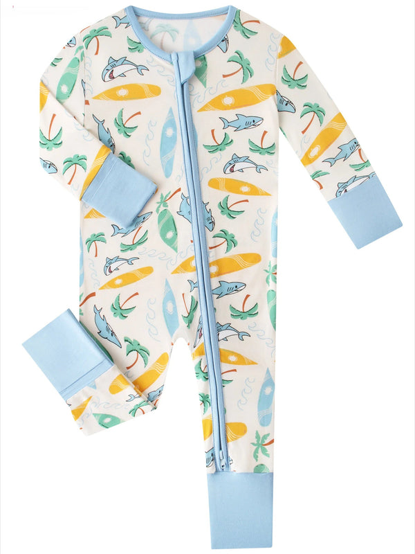 A baby long-sleeve footless zip-up sleeper with a light blue trim and cuffs, featuring an all-over ocean-themed print with surfboards, palm trees, palm leaves, and dolphins on a cream background.