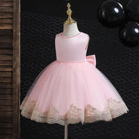 pink elegant baby girl party dress with gold lace trim on a toddler-sized mannequin