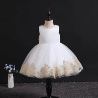 elegant baby girl party dress in white with gold lace trim displayed on mannequin