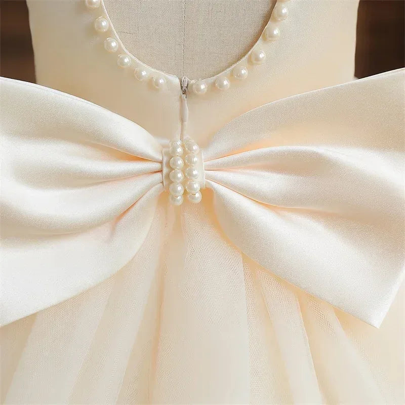 cream elegant V-back dress for girls with pearl neckline and large satin bow detail